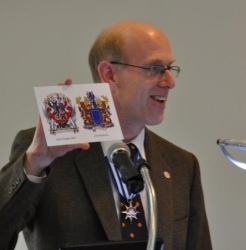 John Neill at podium displaying postcard