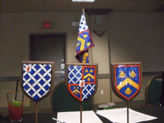 three table shields in front of a banner